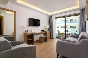 Habitación de hotel moderna con sofá, escritorio, televisión y balcón con vistas.