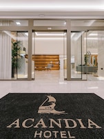 Entrada de hotel com um tapete preto contendo a inscrição 