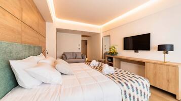 Quarto de hotel moderno com uma cama grande, um sofá, uma TV e uma mesa de escritório com uma luminária.