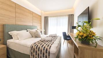A modern hotel room with a large bed, a desk, and a TV.
