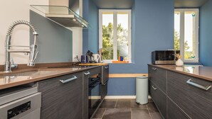 A modern kitchen with dark wood cabinets, stainless steel appliances, and a window providing natural light. - holiday home with private pool and large covered terrace. (La Bachellerie)