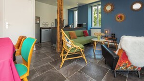 A modern living room with a green sofa, wicker chairs, a black sofa, and a dining area with colorful chairs. - holiday home with private pool and large covered terrace. (La Bachellerie)