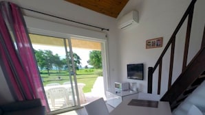 Una sala de estar moderna con una mesa y sillas blancas, un sofá gris, un televisor y una escalera.