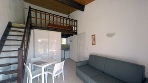 Un espacio habitable compacto con comedor, sofá y una escalera que lleva a un nivel superior.