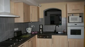 Una cocina con armarios de madera, estufa, microondas y lavavajillas.