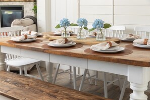 Een eettafel gedekt met borden, servetten en vazen vol bloemen.