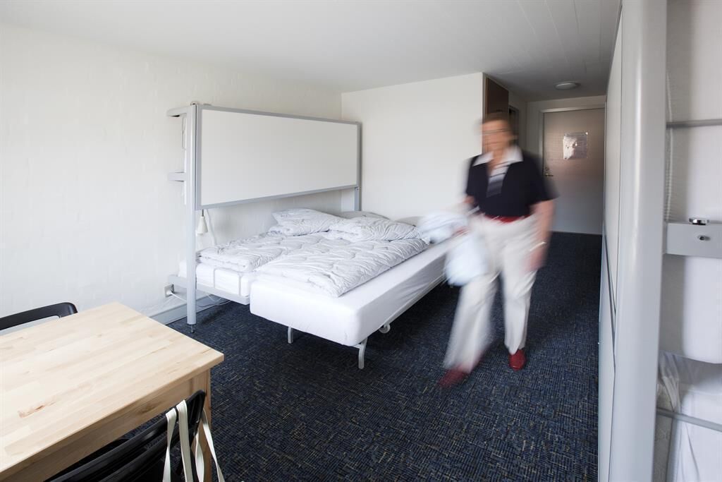 Habitació d'hotel amb un llit, una taula i un refrigerador.