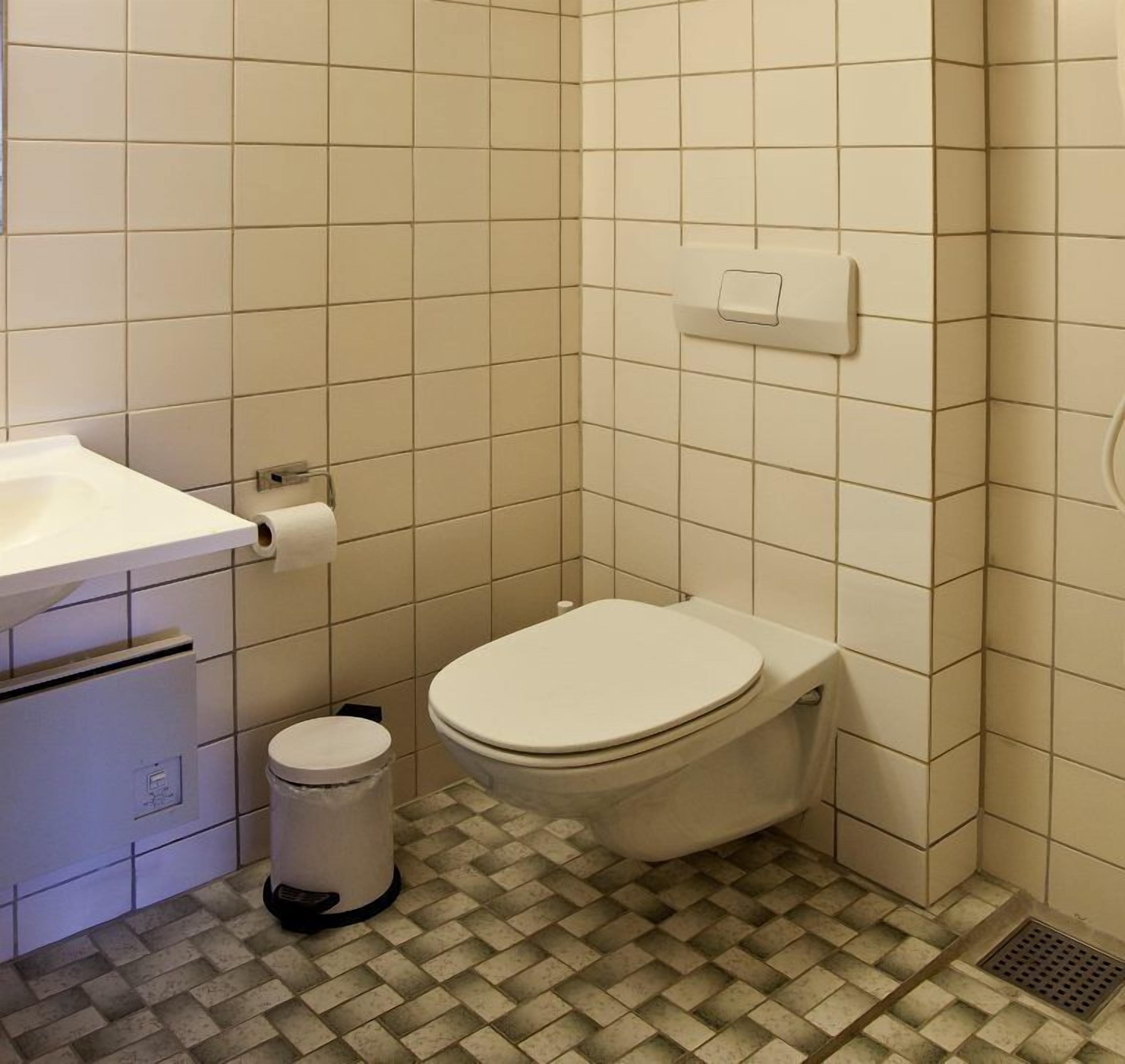 A small bathroom with a toilet, a sink, and a trash can.