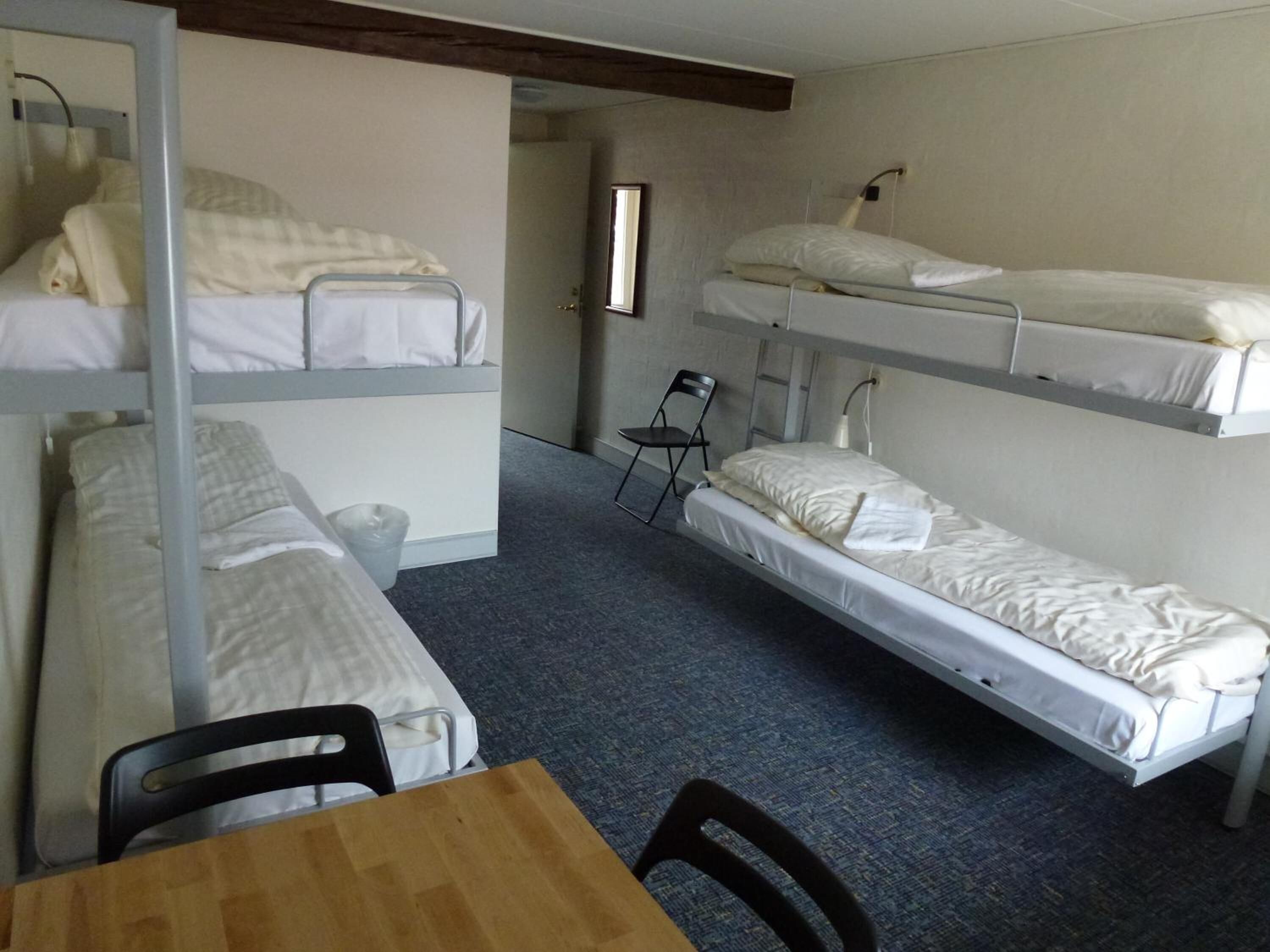 A dormitory room with bunk beds, a small table, and chairs.