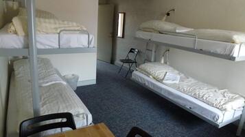 A dormitory room with bunk beds, a small table, and chairs.