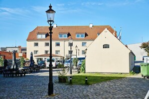 A cobblestone courtyard with a lamp post, a building with a tiled roof, and parked cars. - Danhostel Frederikshavn City (Frederikshavn)