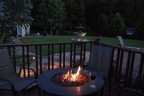 An outdoor patio with a round table, two chairs, a fire pit, and a fountain. - Spacious suite with fenced back yard, deck, gas grill, fireplaces and splash pad (Athens)