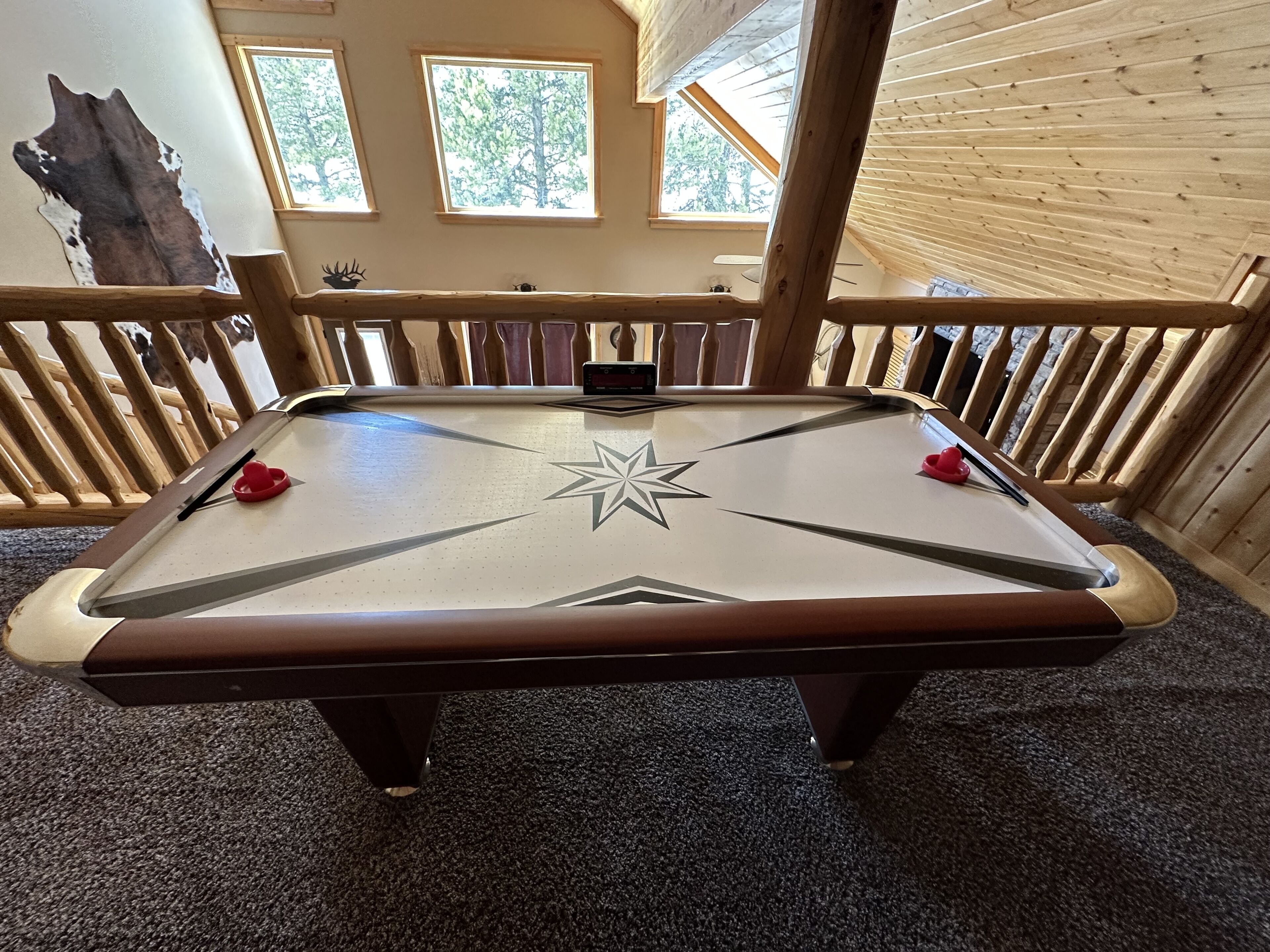 A pool table with a star design in the center, surrounded by a wooden railing.