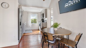 Une cuisine moderne avec un coin repas, une horloge et un panneau indiquant : « Restez au chaud sous votre couette ».