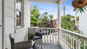 A porch with wicker furniture and a hanging planter. - Casa Bella Suite B | 3 Blocks to King Street (Charleston)