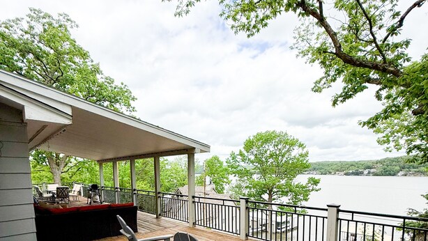 A wooden deck with outdoor furniture, a covered seating area, and a view of a lake. - Ozark Outing - a spectacular view of the Lake of the Ozarks (Roach)