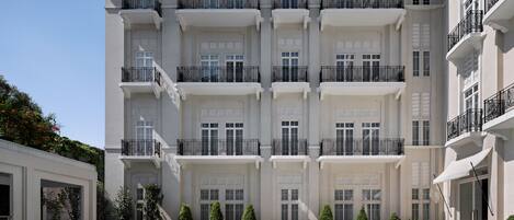 A multi-story hotel with a swimming pool, balconies, and a well-maintained garden.