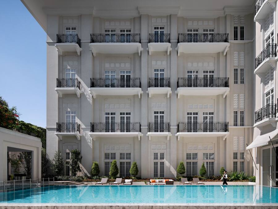 Um hotel com vários andares, piscina, varandas e um jardim bem cuidado.