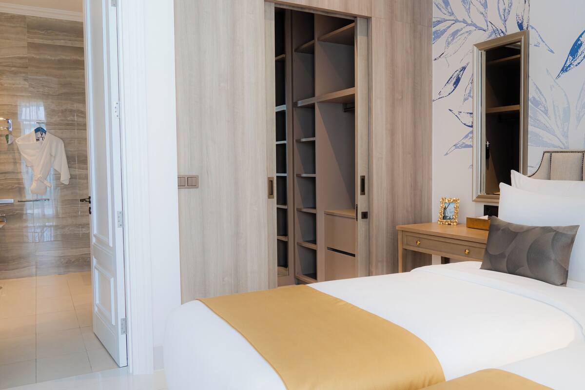 A hotel room with a large bed, a wardrobe, a bedside table, and a mirror.