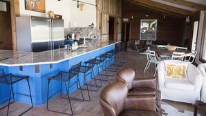 Una cocina con barra, taburetes de bar, un sofá blanco y un sillón de cuero marrón.