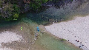 Vista aérea de una playa con kayaks y gente nadando.