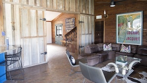 Un interior rústico con una escalera de madera, sofás de cuero y una mesa de centro de vidrio.