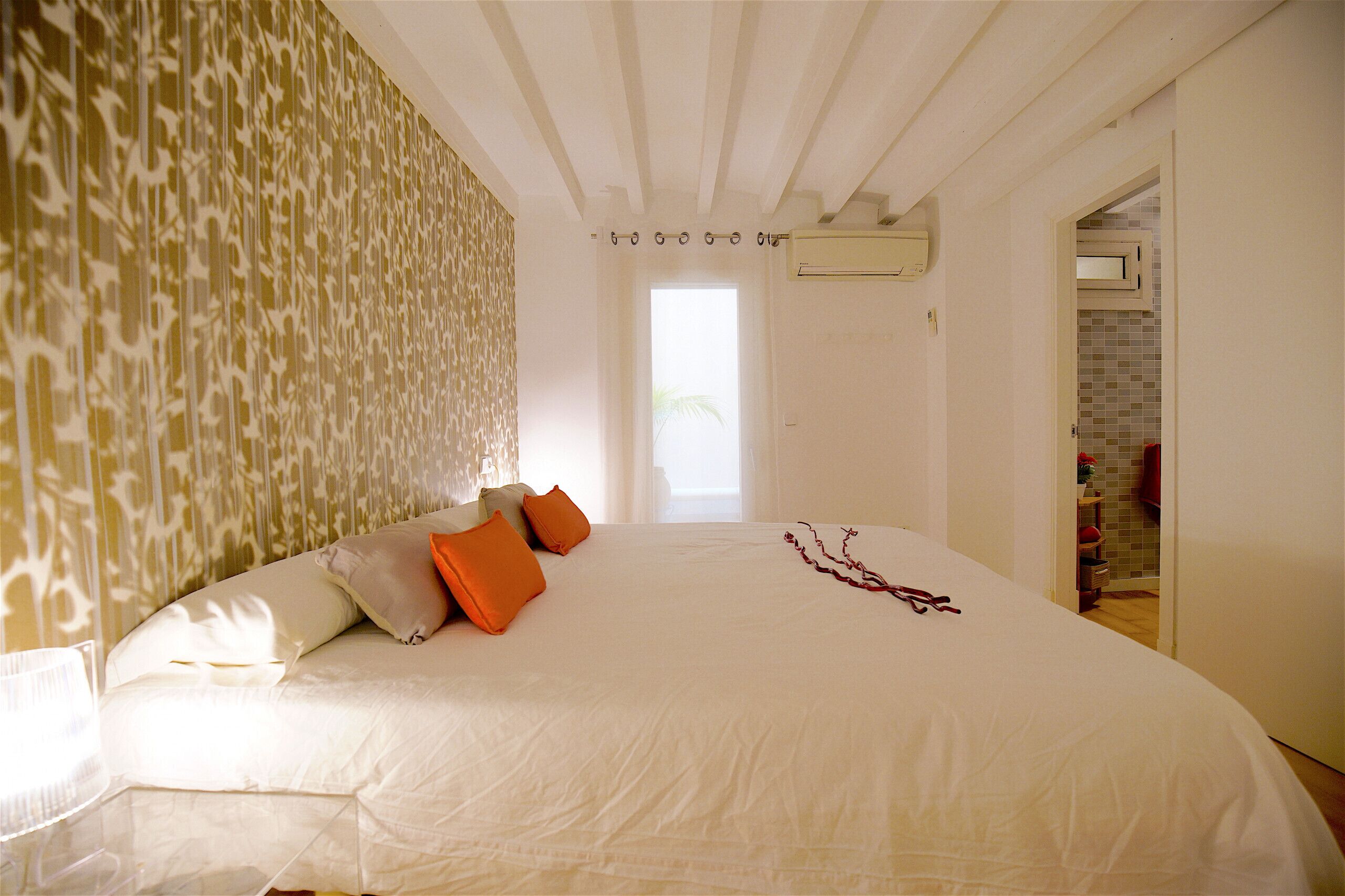 Un dormitorio con una cama grande, un papel tapiz estampado y vistas al exterior.