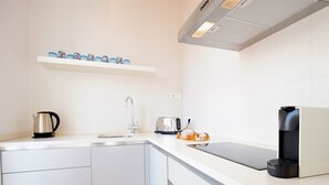 A modern kitchen with a sink, a kettle, a toaster, and a coffee maker.