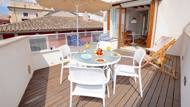 A covered outdoor dining area with a table, chairs, and umbrellas.