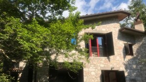 A stone building with a balcony and a small outdoor seating area.