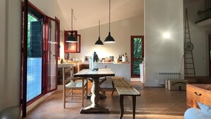 A spacious kitchen with wooden flooring, a dining table, and pendant lights.