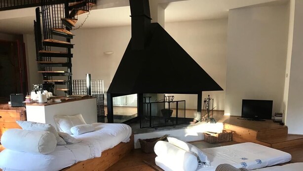 A modern living room with a large fireplace, wooden furniture, and a television.