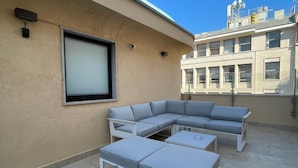 A rooftop patio with a sectional sofa, a coffee table, and a flat-screen TV.