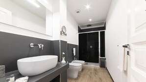 A modern bathroom with a large white sink, a toilet, and a shower.