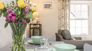 Una mesa de comedor con un jarrón transparente de flores, una lámpara y un cuenco.