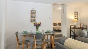 Un espacio habitable compacto con zona de comedor, sofá y cama.