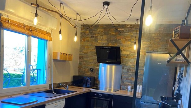 A modern kitchen with a stone wall backsplash, stainless steel appliances, and a wooden countertop.