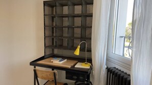A study area with a desk, chair, bookshelf, lamp, and radiator.