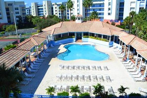Ein Resort mit einem zentral gelegenen Schwimmbad, umgeben von Liegestühlen und einem überdachten Bereich mit einer Kachelterrasse.