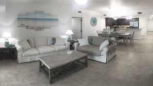 A living room with two sofas, a coffee table, and a dining area with chairs and a table.