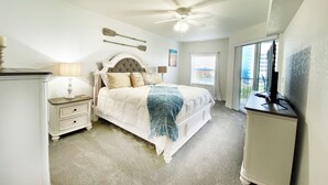 A bedroom with a bed, nightstands, a ceiling fan, a window, and a TV.