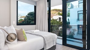 Une chambre moderne avec un grand lit, une vue sur l’extérieur et un balcon.