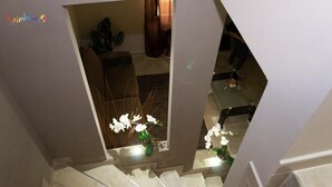 Una escalera de diseño moderno que lleva a una habitación con una planta y una mesa.