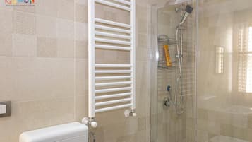 A bathroom with a glass-enclosed shower, a white towel rack, and a toilet.