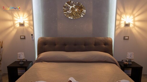 Una habitación de hotel con una cama grande, dos mesitas de noche y apliques de pared.