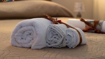 A neatly rolled white towel with a brown band tied around it, placed on a textured bedspread.