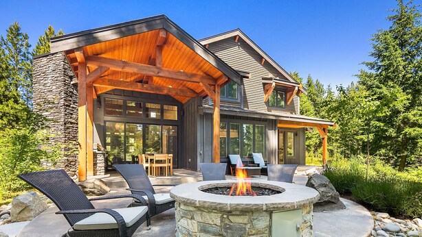 A modern house with a stone fireplace, outdoor seating, and a covered patio area.