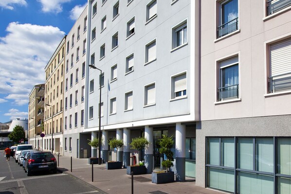A multi-story hotel with a modern facade, large windows, and a row of potted plants along the sidewalk. - Séjours & Affaires Paris Vincennes (Vincennes)
