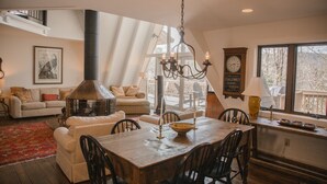 Una sala acogedora con chimenea, una mesa de comedor y un ventanal grande.