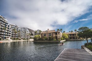 A waterfront hotel with multiple balconies, a dock, and a calm river. - Elegant Waterfront Apartment with No Loadshedding (Cape Town)